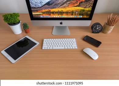 PHATTHALUNG, THAILAND - MARCH 24, 2018: IMac Computers, IPhone, IPad, Plant Vase, Cactus, Pencils  And Clock On Wooden Table, Created By Apple Inc.