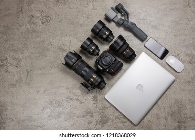 PHATTHALUNG, THAILAND - October 25, 2018 :  Photography equipment on bare mortar background, DSLR camera Nikon D810, DJI Osmo mobile 2, iPhone X,  Lenses, Macbook Pro  and Magic mouse.