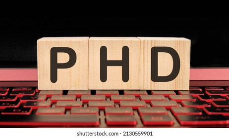 PhD the inscription on wooden cubes on the illuminated laptop keyboard.