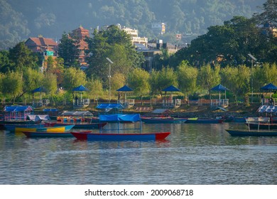 Phewa Lake view from the boat; colorful boats floating on the Lake and people hanging around on bank of the lake; famous tourist destination of Pokhara, Nepal.