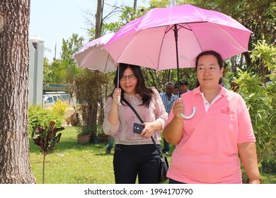 Phichit, Thailand - March 31, 2019: A Fat Woman, Dressed In A Pink Umbrella, Stood In Front Of Another Smiling Woman In The Sun In The Garden.