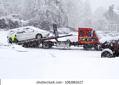 Philadelphia, PA, USA - March 7, 2018: A flatbed tow truck removes a stranded vehicle during a late winter blizzard in Philadelphia, Pennsylvania.