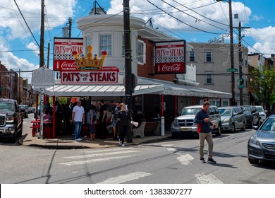 Philadelphia, PA--April 21, 2019; People Standing In Line At Red And White Building That Is Location Of Pats King Of Steaks An Iconic Philadelphia Cheese Steak Restaurant On City's South Side.