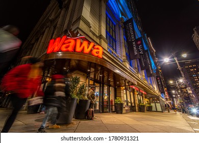 Philadelphia, PA--Feb 4, 2020; Time Exposure Captures Blurred Motion Of Customers Entering And Leaving Front Doors Of Wawa Convenience Store Downtown In Winter At Night.