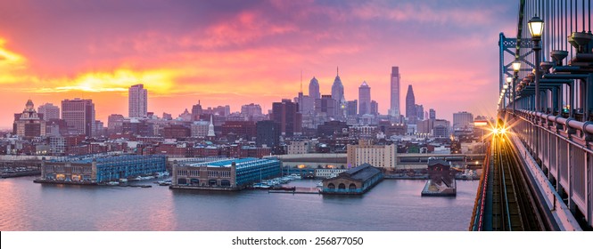 Philadelphia panorama under a hazy purple sunset. An incoming train crosses Ben Franklin Bridge. - Powered by Shutterstock