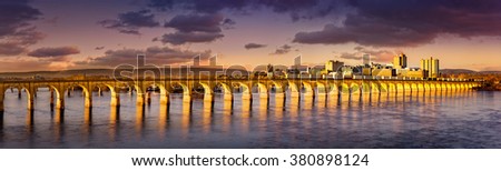 Philadelphia and Reading Railroad Bridge crosses Susquehanna river at sunset. Harrisburg skyline shines under a late afternoon light.