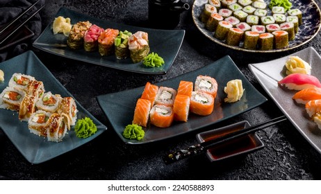 Philadelphia roll with salmon, roll canada with eel and salmon, maki rolls, sushi gunkans, sushi with salmon, tuna on dark stone table