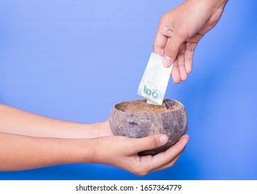 
Philanthropist Is Giving Money Into A Bowl To The Beggar.