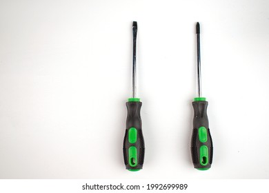 Phillips and flathead screwdrivers are parallel. Black rubber handle with green plastic. Isolate. Copy space. Flat lay.