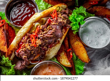 Philly cheese steak sandwich with meat, vegetables, cheese and sause on wooden table. street food