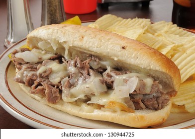 A philly cheese steak sandwich with potato chips