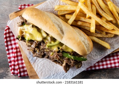 Philly cheesesteak sandwich with beef, cheese,green pepers and caramelized onion on wooden table