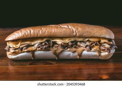 Philly Steak Sandwich With Cheese And Chipotle Sauce On A Wooden Table With A Long Bun