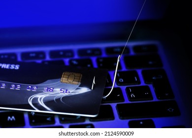 Phishing Credit Cards - Piles of credit cards with fish hook on computer keyboard. Dark Background.