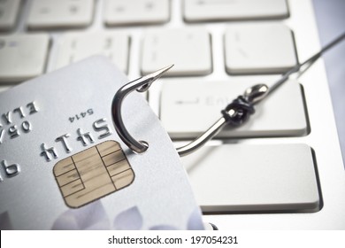 phishing - fish hook with a credit card on white computer keyboard