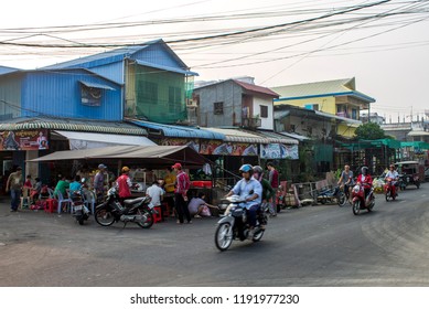 Phnom Penh, Cambodia - 02.17.2018: Motorcycle Traffic Zips Past Locals Having Breakfast At A Street Vendor's Stall In The Boeng Keng District.