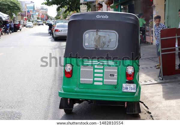 Phnom Penh, Cambodia, August 17, 2019 : Tuk Tuk or\
Taxi tricycle in green color on the road, Lifestyle of traffic in\
Phnom Penh. It is a three-wheeled motorized vehicle used as a taxi\
grab.