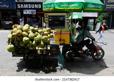Phnom Penh, Cambodia - June 13, 2022: A local vendor is seen on his motorcycle cart loaded with coconuts for selling in a street near Central Market.