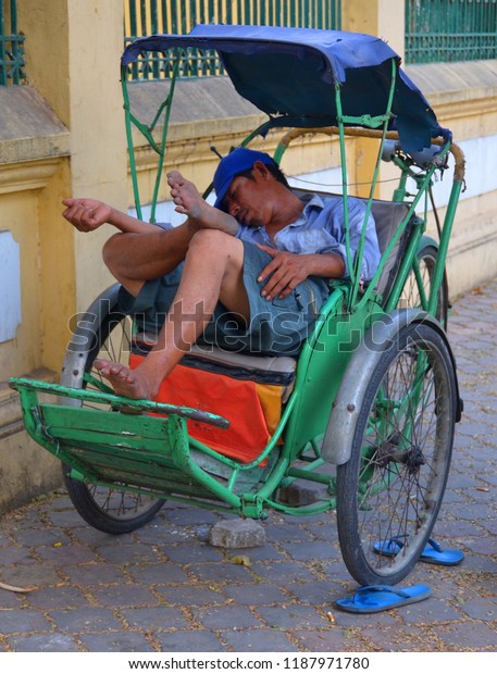 PHNOM PHEN, CAMBODIA MARCH 25 2013: Tuk\
tuk driver sleeps before next customer jumps. The tuk tuk is the\
main affordable transport for many\
tourists.
