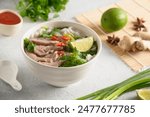 Pho Bo Soup with beef, rice noodles, ginger, lime, chili pepper in bowl on white background. Close up. Vietnamese and Asian cuisine.