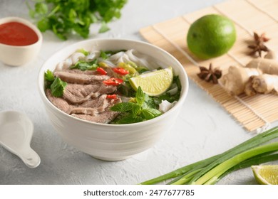 Pho Bo Soup with beef, rice noodles, ginger, lime, chili pepper in bowl on white background. Close up. Vietnamese and Asian cuisine. - Powered by Shutterstock