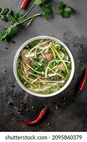 Pho Bo Spicy Broth Or Soup In White Ceramic Bowl With Rice Noodles, Beef Slices And Herbs. Concept Of Vietnamese Food, Top View