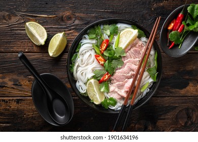 Pho Bo vietnamese soup with beef and noodles on a wooden background, top view
