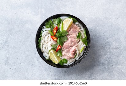 Pho Bo vietnamese soup with beef and rice noodles on a concrete background, top view