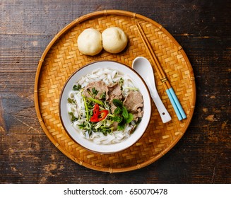 Pho Bo Vietnamese Soup With Beef And Steam Bun Bao On Bamboo Tray On Wooden Background
