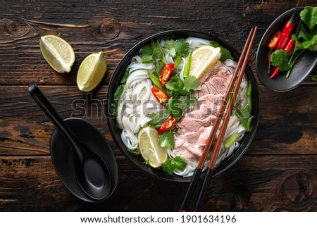 Pho Bo vietnamese soup with beef and noodles on a wooden background, top view