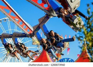 PHOENIX, AZ-USA-10 OCTOBER 2018 People Ride A Spinning Ride That Goes Upside Down At The Arizona State Fair With The Ferris Wheel In The Background.