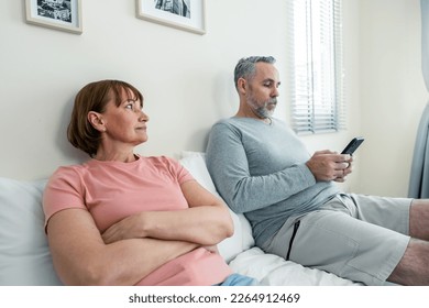 Phone addiction, Caucasian husband doesn't pay attention to his wife. Family problem-separation, Senior elderly mature couple sitting on bed and using smartphone, ignore each other in bedroom at home. - Powered by Shutterstock