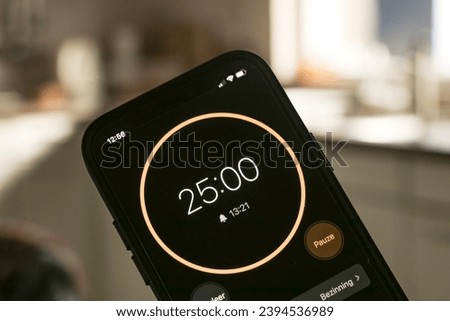 A phone with a black and orange 25-minute timer to study with the pomodoro method on a blurry background. Translation: Pauze means Pause in Dutch. 