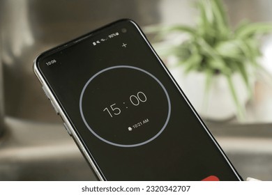 A phone with a black and white 15-minute timer to study with the pomodoro method on a blurry background - Shutterstock ID 2320342707