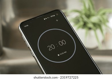 A phone with a black and white 20-minute timer to study with the pomodoro method on a blurry background