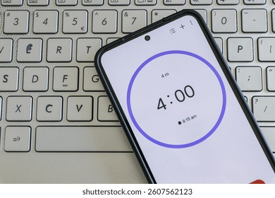 A phone with a black and white 4-minute timer to study with pomodoro method on laptop keyboard, study business background