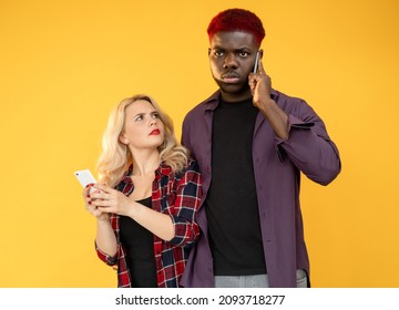 Phone Call. Bad News. Unexpected Problem. Booking Cancellation. Multiethnic Couple Of Confused Man On Cell Conversation With Suspicious Woman Isolated On Orange Background.