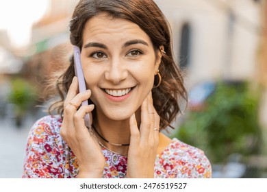 Phone call, good news, gossip. Happy surprised Caucasian young woman in pleasant conversation on smartphone, enjoying talking with friend outdoors. Young girl standing in city street. Town lifestyles - Powered by Shutterstock