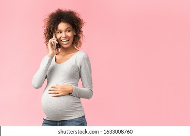 Phone call. Smiling afro pregnant woman consulting with doctor, pink background with free space - Powered by Shutterstock