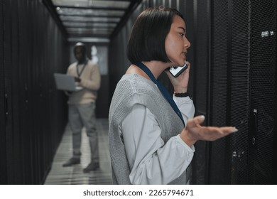 Phone call, technician and woman in a server room for maintenance, repairs or data analysis. Systems, technology and Asian female engineer on mobile conversation while checking power of cable service - Powered by Shutterstock