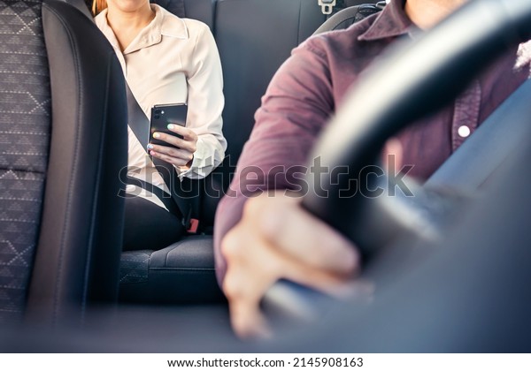 Phone in car or taxi. Passenger woman using\
cellphone in back seat of cab. Driver and customer. Rideshare\
mobile app. Professional business person travel to work, commute.\
Lady sitting in the\
backseat