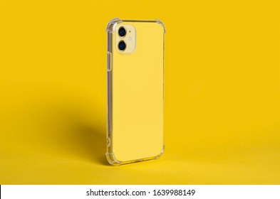 Phone Case Mock Up Side View. Yellow IPhone In Clear Silicone Case Isolated On Yellow Background, Rotated Position. Smartphone Perspective View