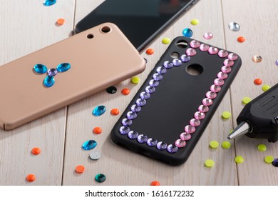 Phone Cases Being Decorated With Various Rhinestones. Creative DIY Project For Girl.