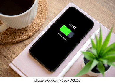 Phone with charged battery on the screen background of wooden table in the office