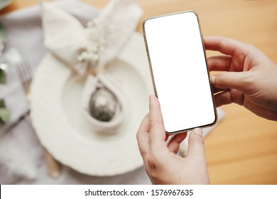 Phone with empty screen on background of stylish Easter flat lay table setting with egg in easter bunny napkin. Space for text. Modern Easter table decorations, mockup. Seasons greetings - Powered by Shutterstock - Get 15% off with code: PIKWIZARD15
