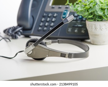 Phone, Fax, Headphones And Indoor Flower Decor On A White Background. Close-up. Work, Office, Communications, Freelance. There Are No People In The Photo.