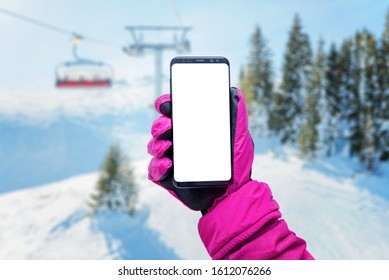 Phone in girl hand with glove on a ski lift. Isolated screen for mockup. Ski lift, resort and slopes in background
