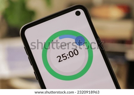 A phone with a green 25-minute timer to study with the pomodoro method on a blurry background. Perfect for students planning their time studying, doing homework, being productive.