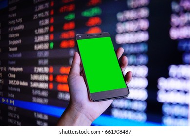 The phone with green screen in the hand and the stock board in background                                 - Shutterstock ID 661908487