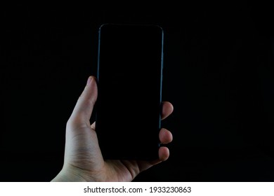 Phone in hand on a black background.